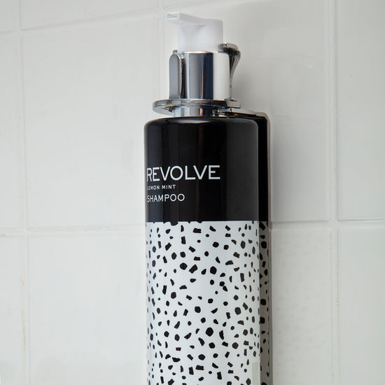 Wall-mounted REVOLVE: TERRAZZO 12oz Shampoo dispenser, offering a sleek and convenient hair care solution for guests.