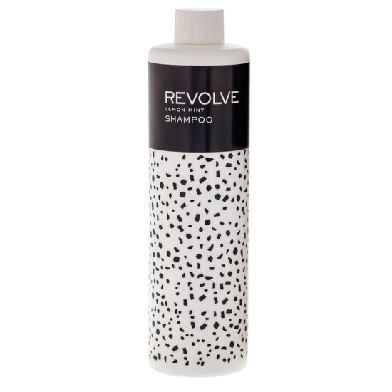 The REVOLVE: TERRAZZO 12oz Shampoo features a sleek bottle of premium shampoo with a refreshing formula, designed for an elevated hair care experience in hospitality settings.